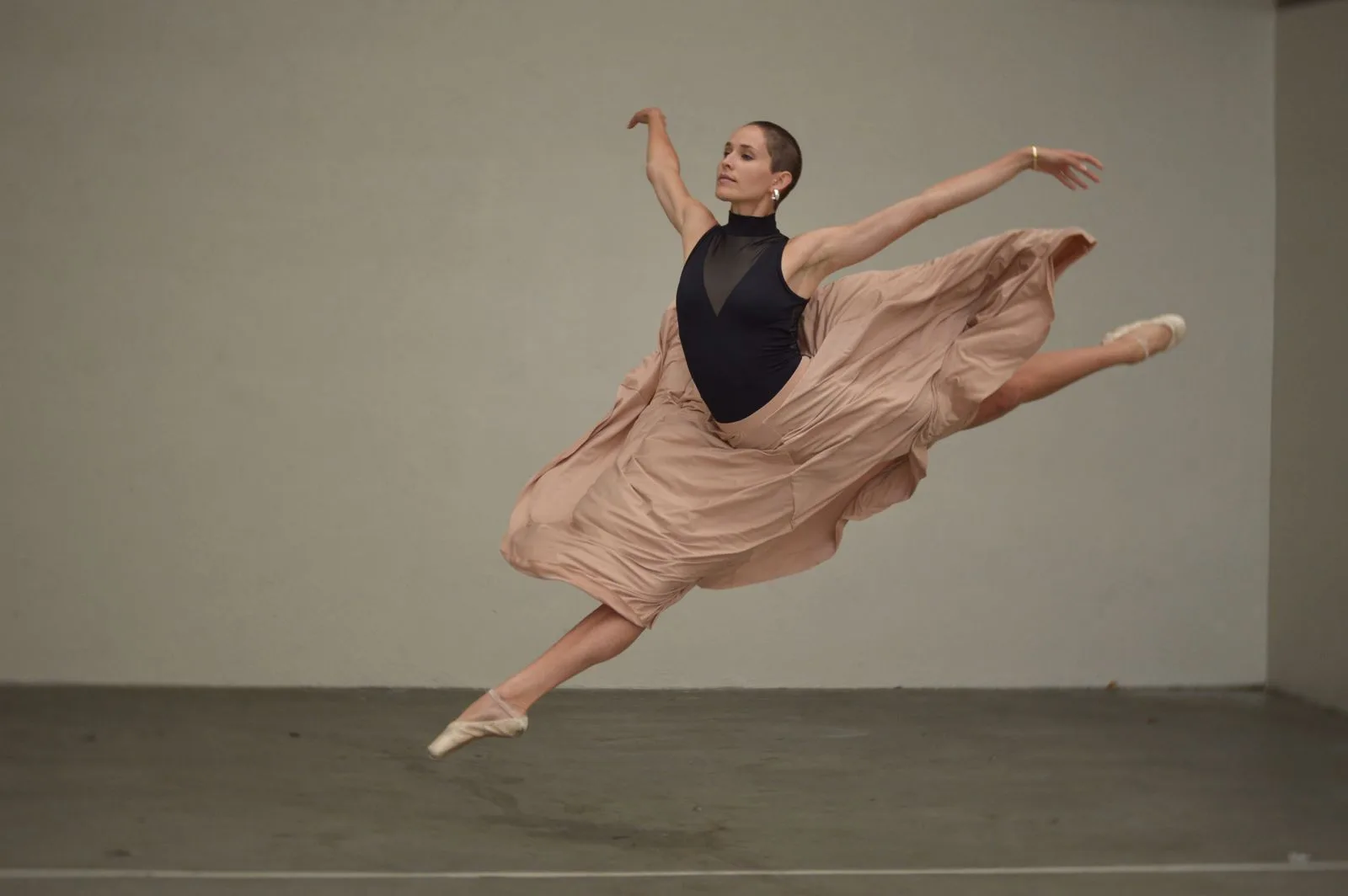 Eine erwachsene Balletttänzerin im Sprung der Probe.